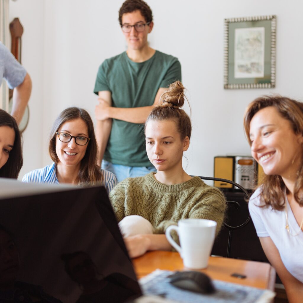 group of students working together around a computer