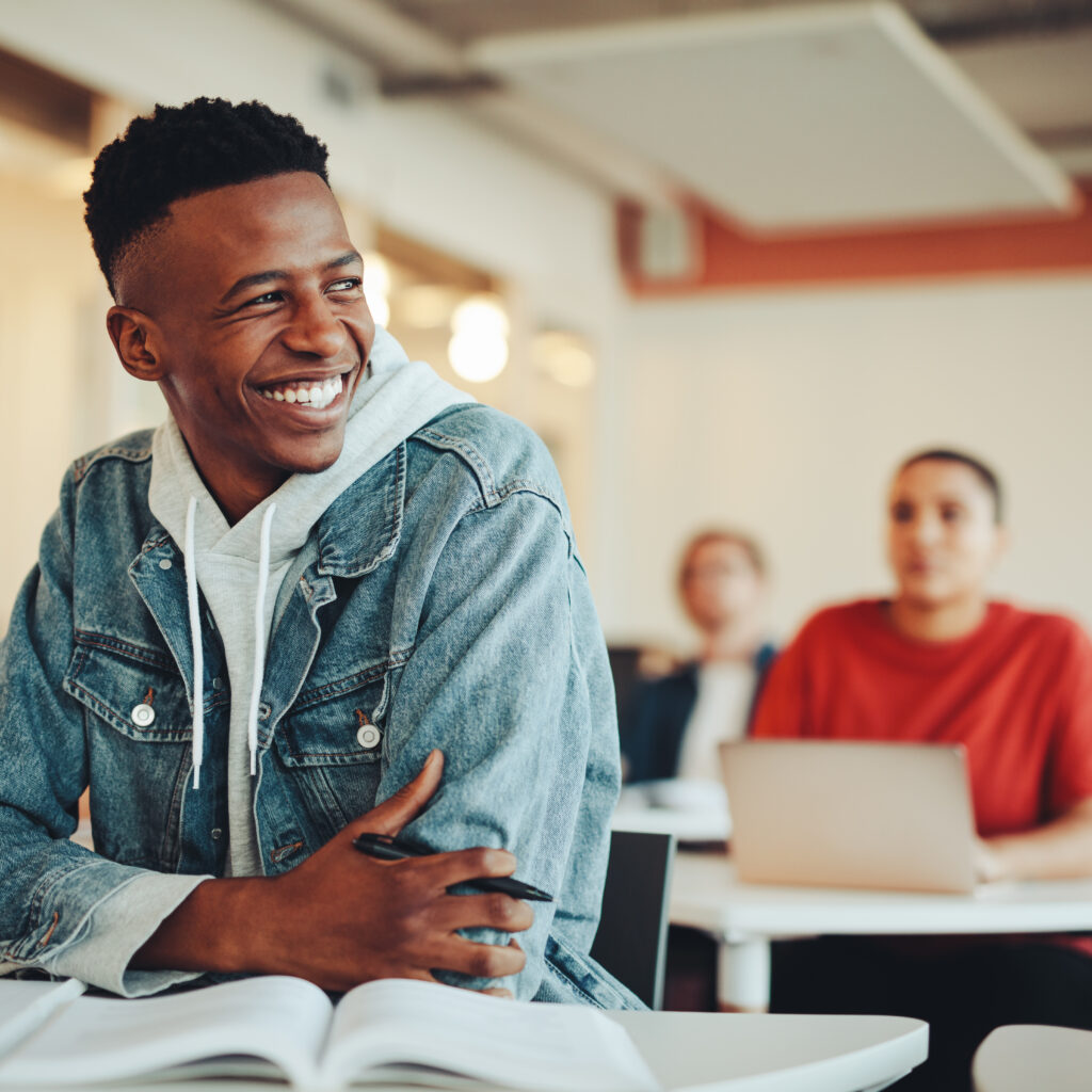 Smiling male student sitting in university classroom
